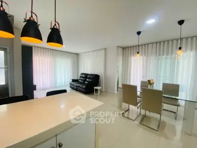 Spacious modern living and dining area with elegant lighting and sleek furniture.