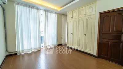 Spacious bedroom with elegant wooden flooring and ample natural light from large windows.