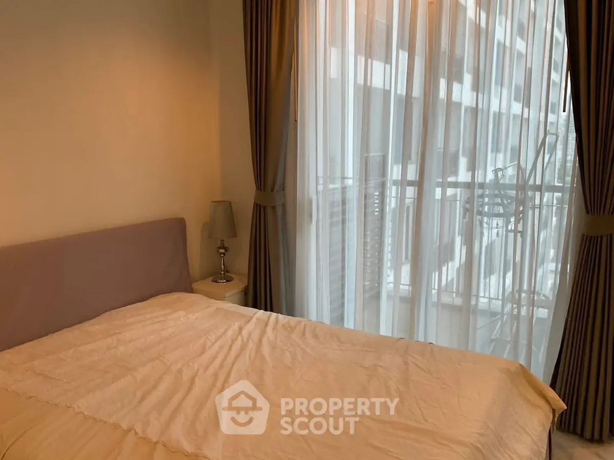 Cozy bedroom with large window and sheer curtains offering a serene view.