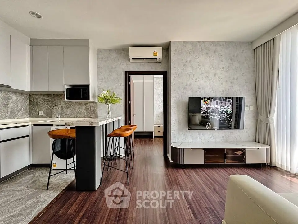 Modern living room with open kitchen, stylish decor, and hardwood floors in a contemporary apartment.