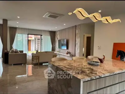 Luxurious open-plan living room with elegant marble flooring and modern lighting, featuring a stylish kitchen island.