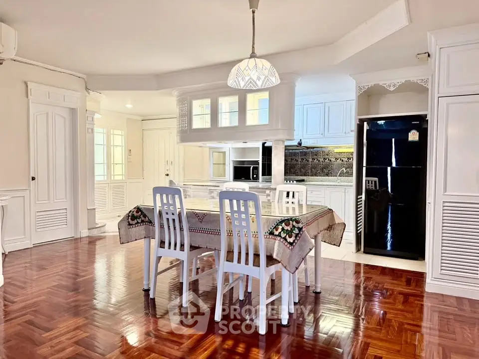 Spacious dining area with elegant wooden flooring and modern kitchen in open layout.