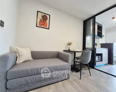 Modern living room with stylish gray sofa and dining area in open-plan apartment.