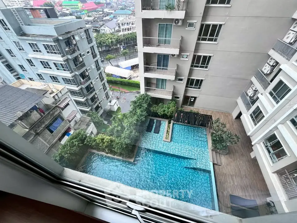 Stunning aerial view of modern apartment complex with pool and lush greenery.