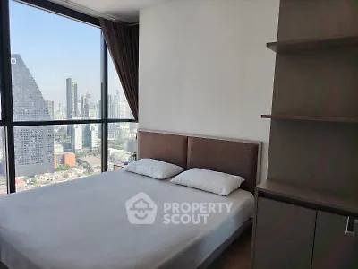 Modern bedroom with city view and large windows in high-rise apartment.