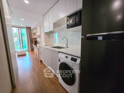 Modern kitchen with washing machine and fridge in open layout apartment