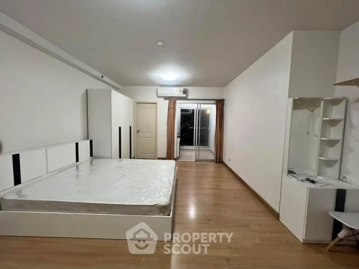 Spacious bedroom with modern furnishings and large window for natural light.