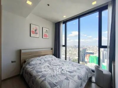 Modern bedroom with stunning city view through floor-to-ceiling windows, featuring stylish decor and cozy bedding.