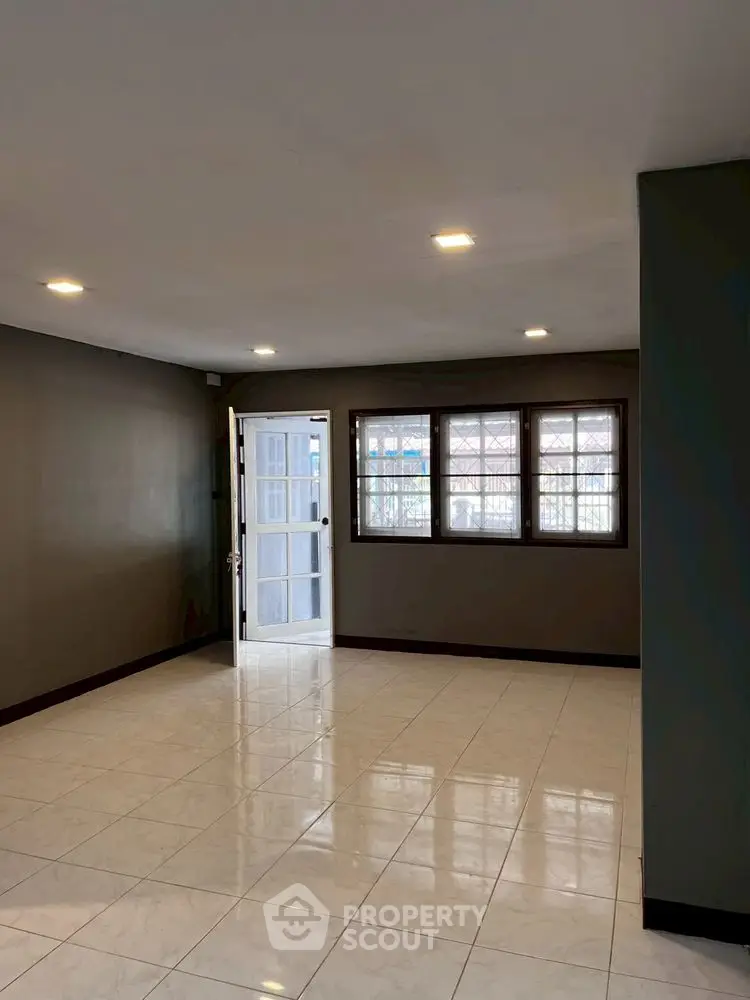 Spacious empty room with tiled floor and large windows for natural light.