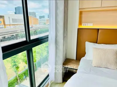 Modern bedroom with large window offering city view and natural light