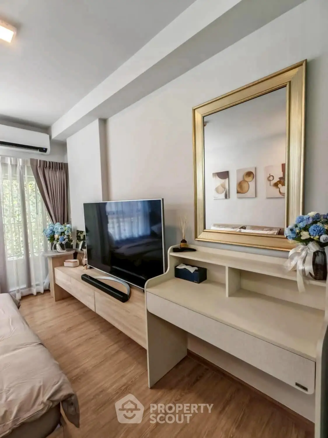 Stylish living room with modern decor, large TV, and elegant mirror reflecting natural light.