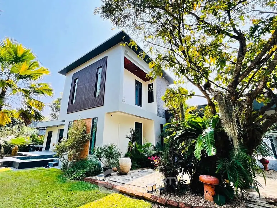 Modern two-story house with lush garden and pool, showcasing contemporary architecture and serene outdoor space.