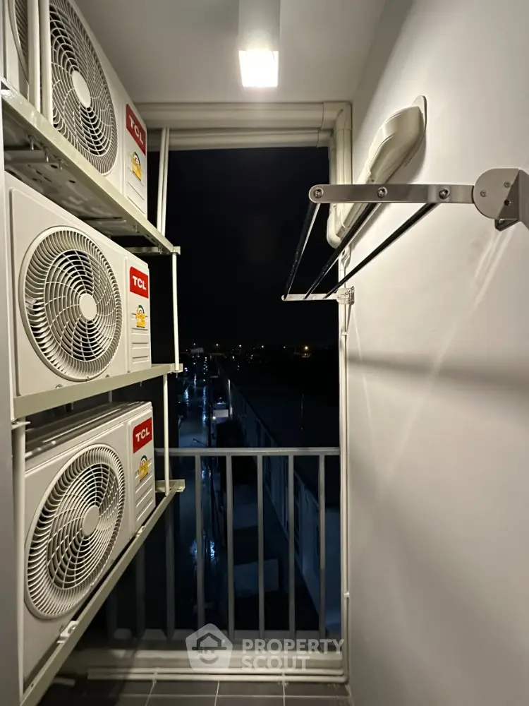 Compact balcony with air conditioning units and city night view, ideal for urban living.
