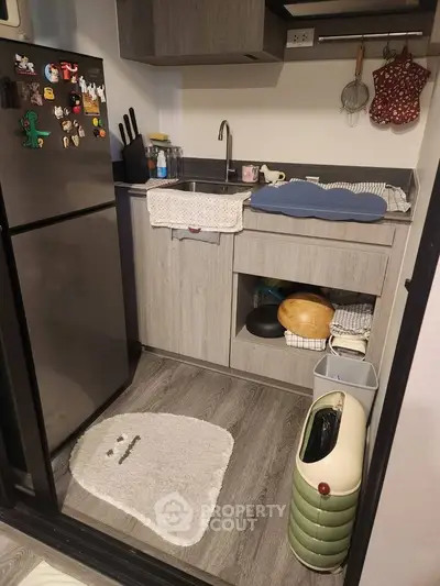 Compact modern kitchen with sleek cabinetry and stainless steel fridge, ideal for urban living.