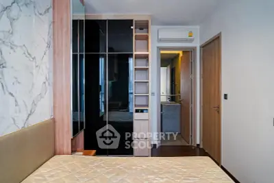 Modern bedroom with built-in wardrobe and ensuite bathroom in stylish apartment.