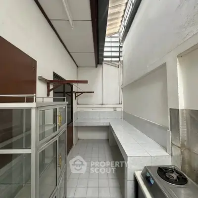 Spacious kitchen with tiled countertops and gas stove, perfect for culinary enthusiasts.