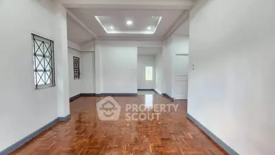 Spacious empty room with parquet flooring and recessed lighting