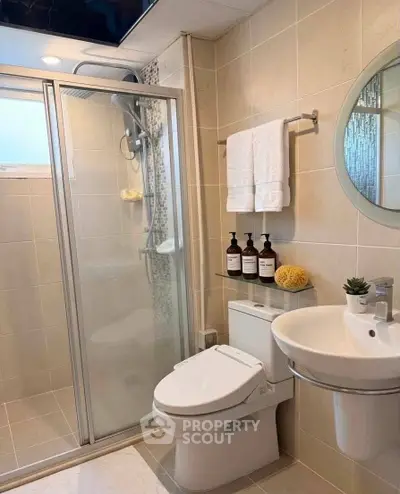 Modern bathroom with glass shower, round mirror, and sleek fixtures in a stylish home.