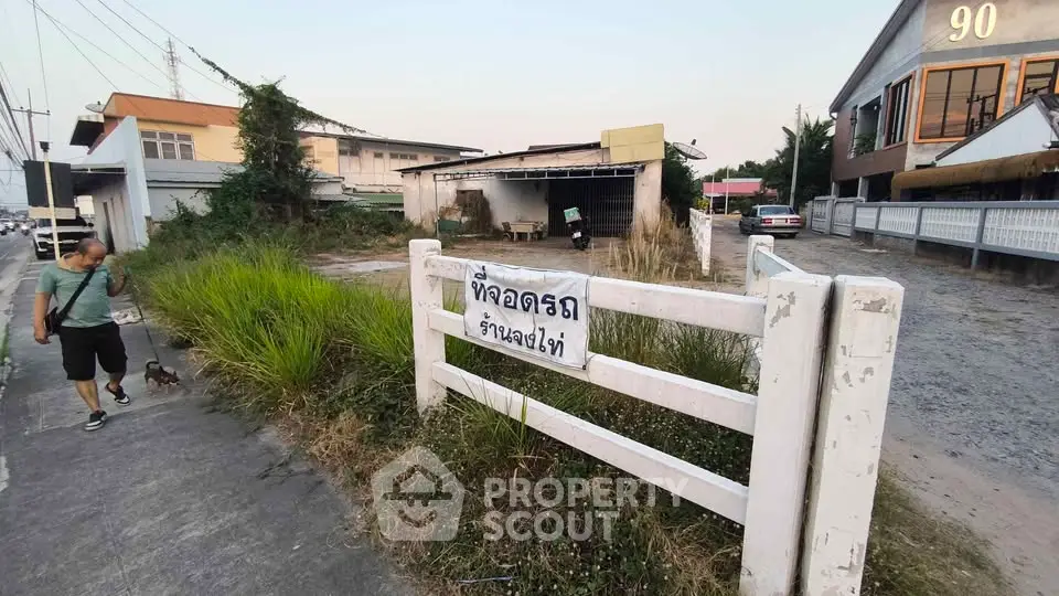 Vacant lot with potential for development in urban area, featuring a fenced boundary and nearby amenities.