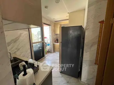 Modern kitchen with marble walls and sleek appliances in a bright apartment.