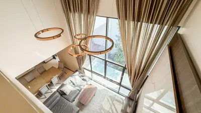 Luxurious living room with high ceilings and large windows, featuring modern lighting and elegant decor.