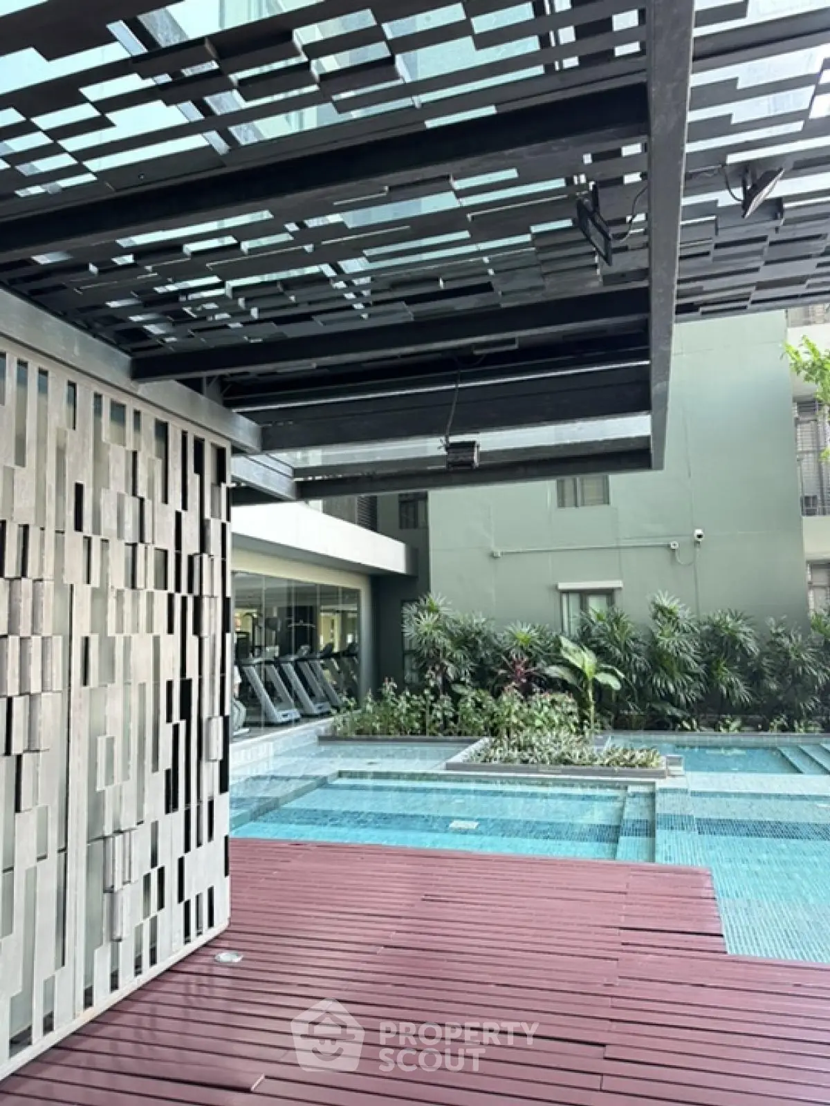 Modern apartment pool area with stylish deck and lush greenery