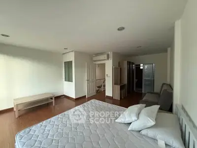 Spacious bedroom with wooden flooring and modern furnishings in a bright apartment.