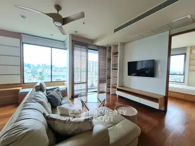 Spacious modern living room with city view, featuring a cozy sectional sofa and wall-mounted TV.