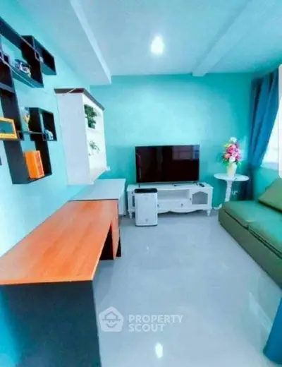 Modern living room with teal walls, sleek furniture, and a flat-screen TV.