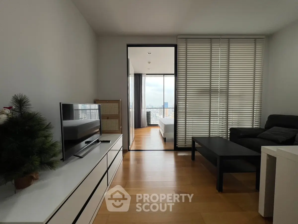 Modern living room with sleek furniture and city view through large windows.