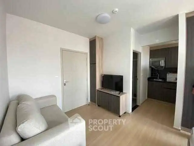 Modern living room with sleek furniture and compact kitchen in open layout apartment.