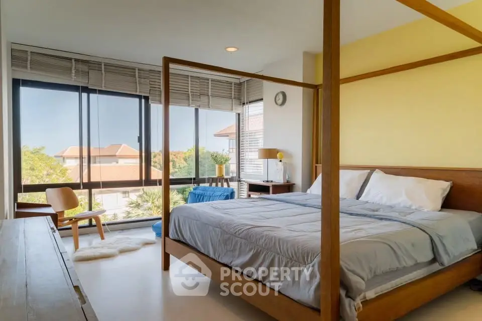 Spacious bedroom with large windows and modern decor, offering a serene view.