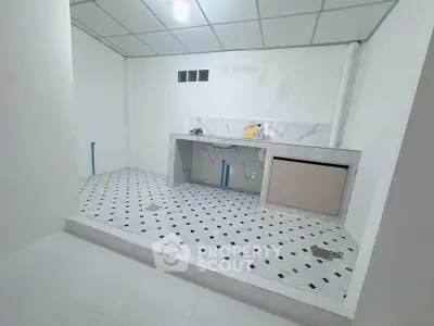 Modern minimalist kitchen under renovation with marble countertops and tiled flooring.