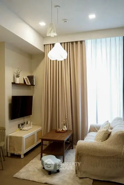 Cozy living room with modern decor, featuring a comfortable sofa, stylish lighting, and a wall-mounted TV.