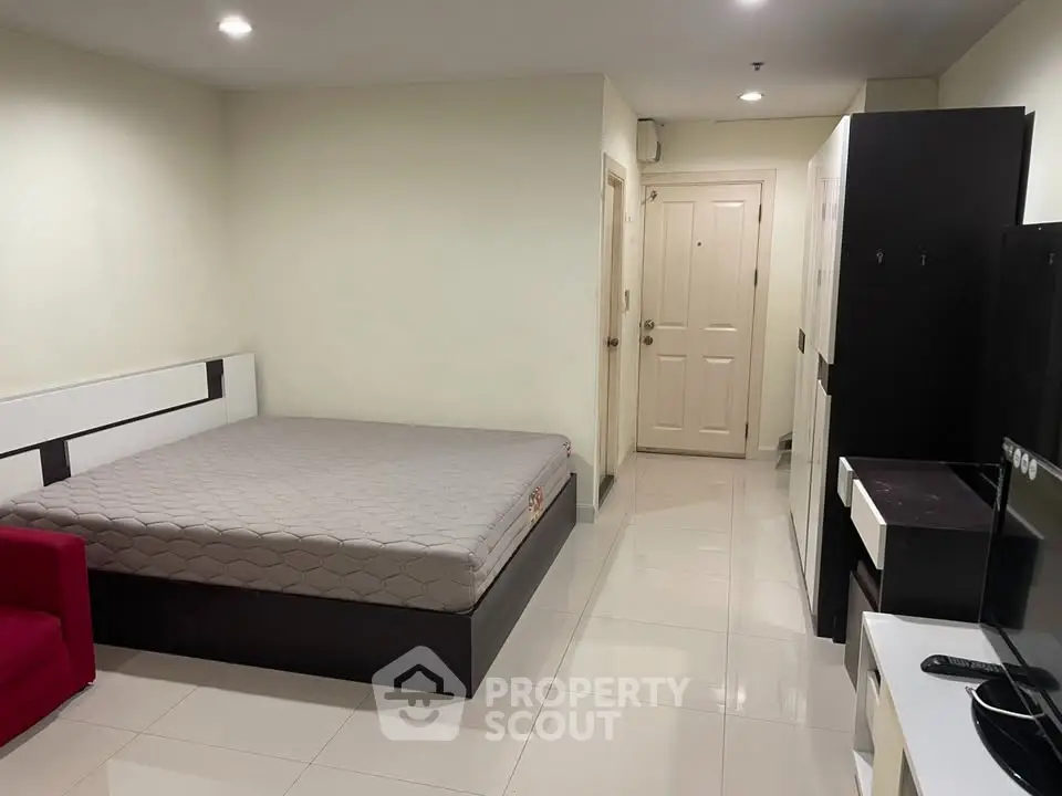 Spacious bedroom with modern furnishings and sleek tile flooring in a contemporary apartment.