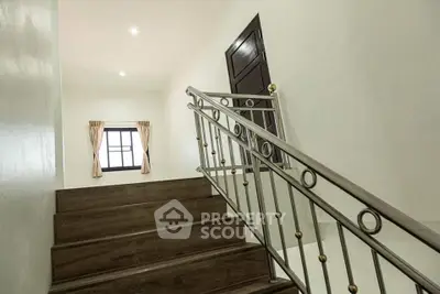 Elegant staircase with wooden steps and decorative railing in a bright hallway.