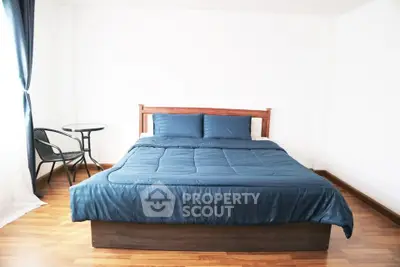 Spacious bedroom with elegant wooden flooring and modern blue bedding.
