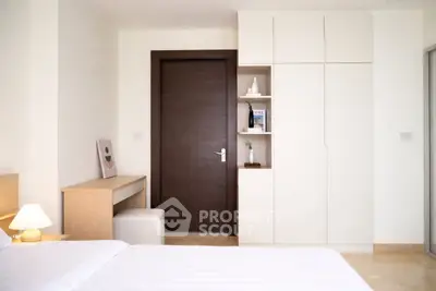 Modern bedroom with sleek wooden door and built-in storage, featuring minimalist decor and soft lighting.