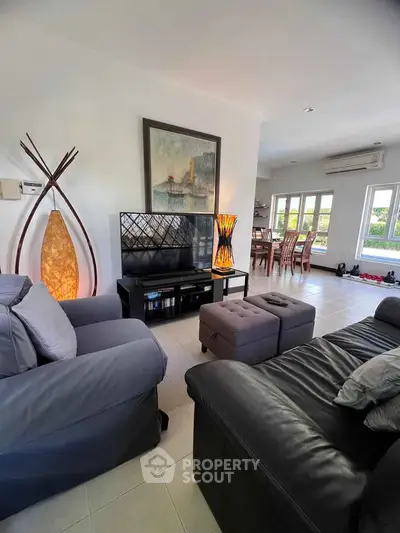 Spacious living room with modern decor and ample natural light, featuring cozy seating and stylish lighting.