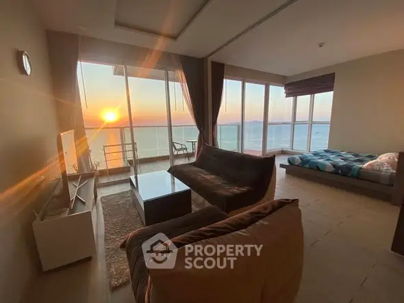 Stunning living room with ocean view and sunset, featuring modern furniture and large windows.