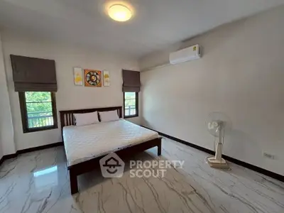 Spacious bedroom with modern decor and air conditioning in a serene setting.