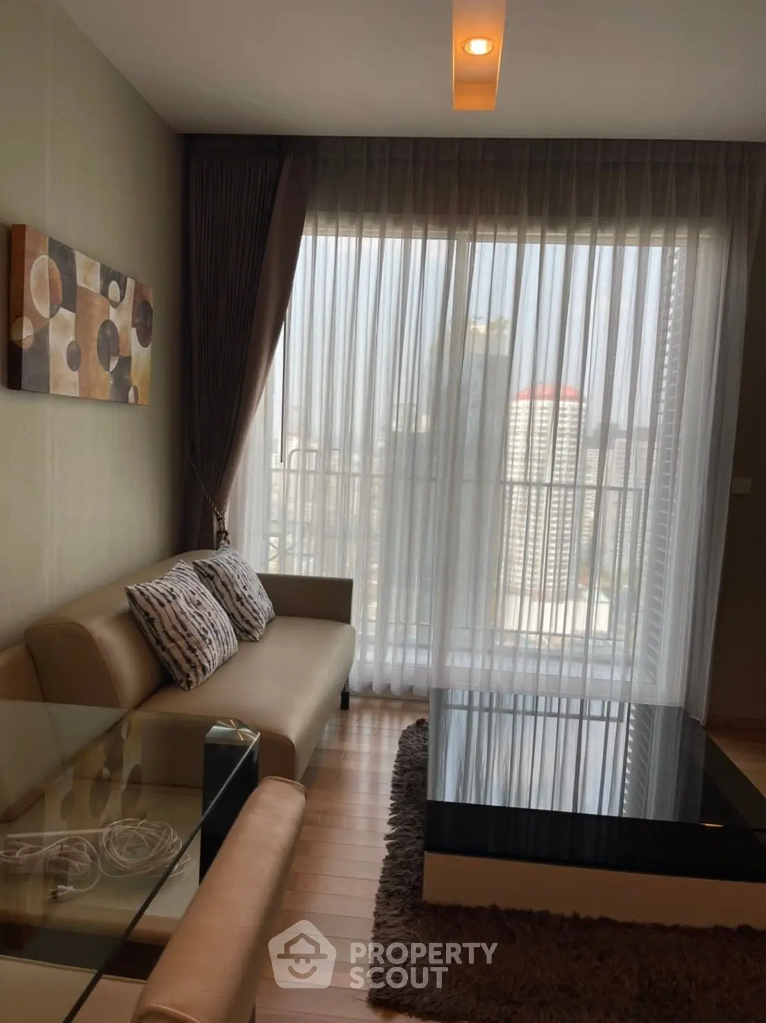 Modern living room with city view, featuring stylish furniture and floor-to-ceiling windows.