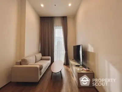 Cozy and modern living room with elegant beige sofa set, sleek white coffee table, and warm wooden flooring, complemented by natural light from the large window.