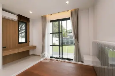 Spacious bedroom with large window and garden view, featuring modern design and wooden flooring.