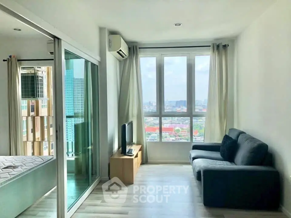 Bright living room with large windows and city view, featuring modern furniture and sleek flooring.