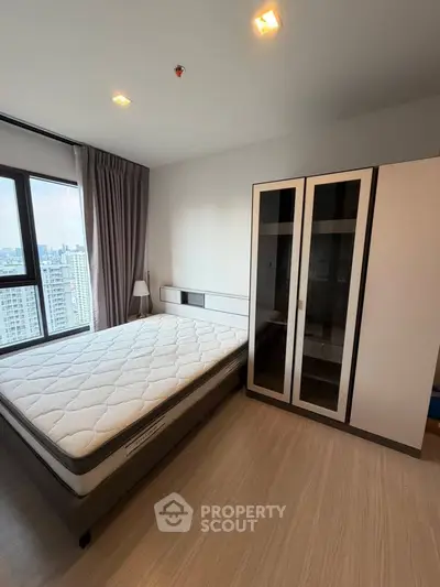 Modern bedroom with city view, featuring a comfortable bed and sleek wardrobe.