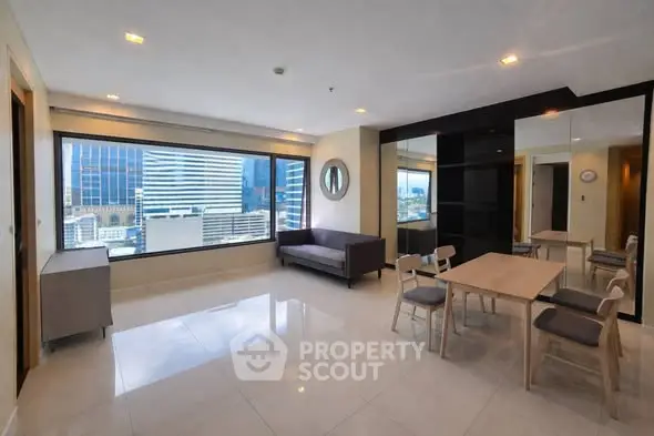 Spacious modern living room with city view and dining area in high-rise apartment.