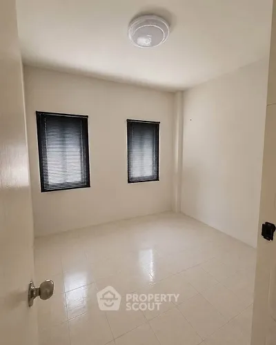 Spacious empty room with tiled floor and two windows, perfect for customization.