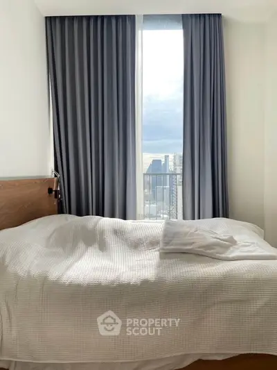 Cozy bedroom with city view through large window and elegant curtains.