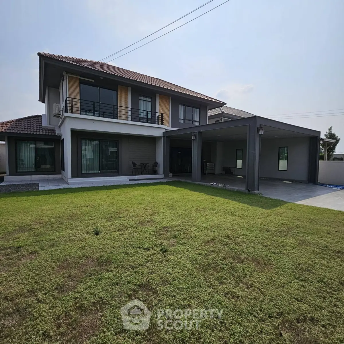 Spacious modern two-story house with large lawn and covered parking area.
